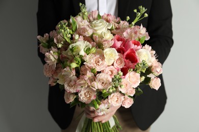 Photo of Man with beautiful bouquet of flowers on grey background, closeup