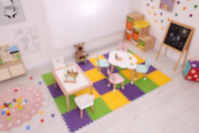 Stylish kindergarten interior with toys and modern furniture, blurred view