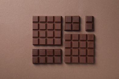 Photo of Tasty milk chocolate on brown background, flat lay