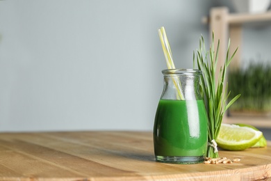 Bottle of juice and fresh wheat grass on table. Space for text
