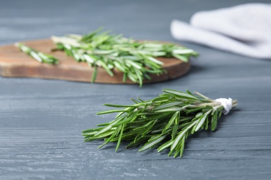 Fresh green rosemary on blue wooden table, space for text