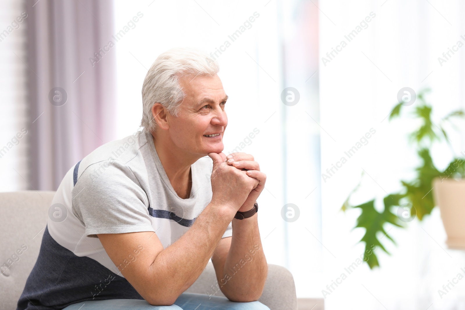 Photo of Portrait of handsome mature man on sofa indoors. Space for text