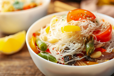 Tasty cooked rice noodles with vegetables on table, closeup