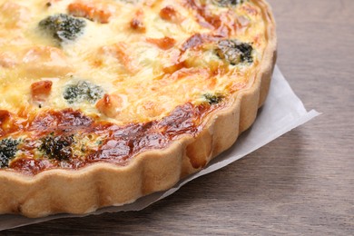 Delicious homemade quiche with salmon and broccoli on wooden table closeup