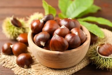 Photo of Fresh sweet edible chestnuts on brown table, closeup