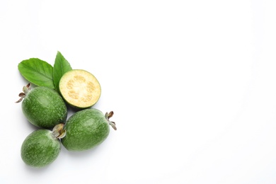 Cut and whole feijoas with leaves on white background, top view
