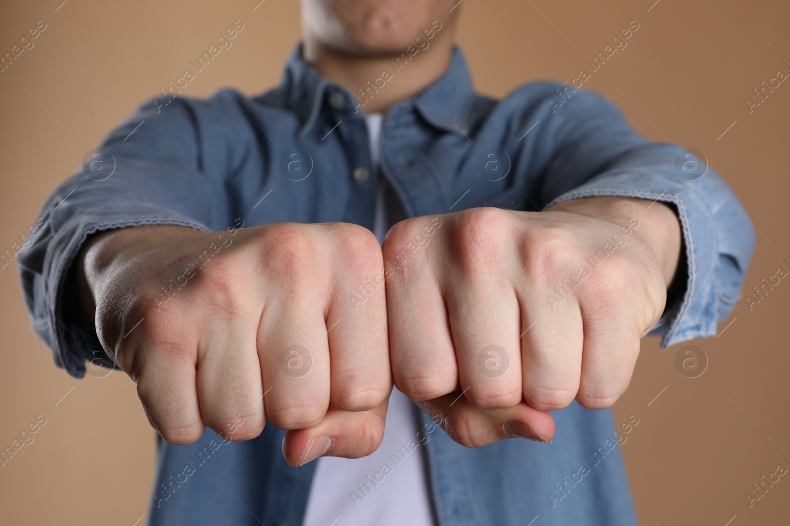 Photo of Man showing fists with space for tattoo on beige background, selective focus