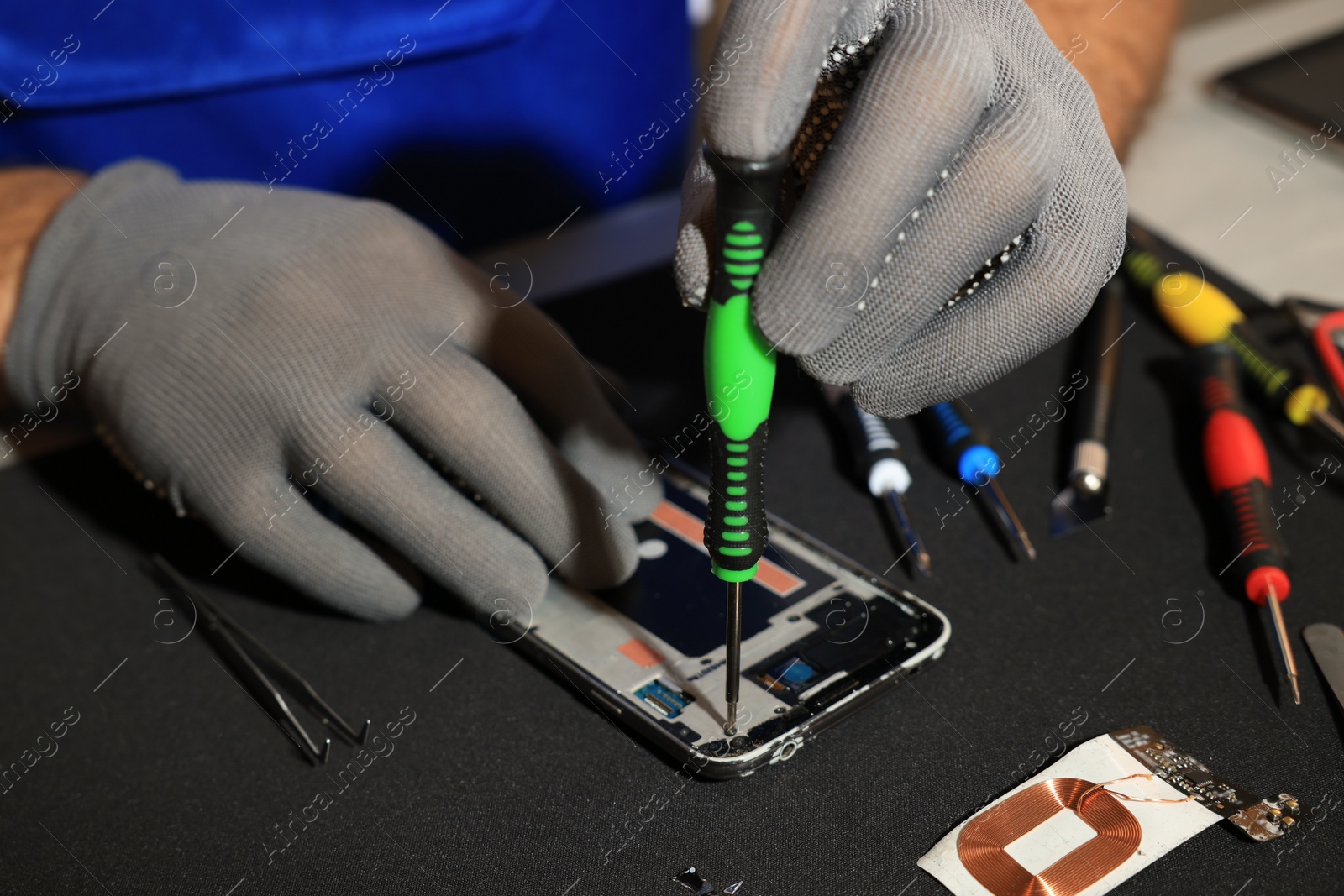 Photo of Technician repairing broken smartphone at table, closeup