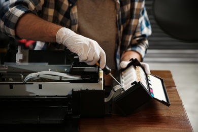 Photo of Repairman with screwdriver fixing modern printer indoors, closeup