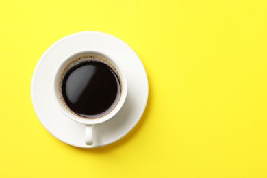 Photo of Cup of aromatic coffee on yellow background, top view. Space for text