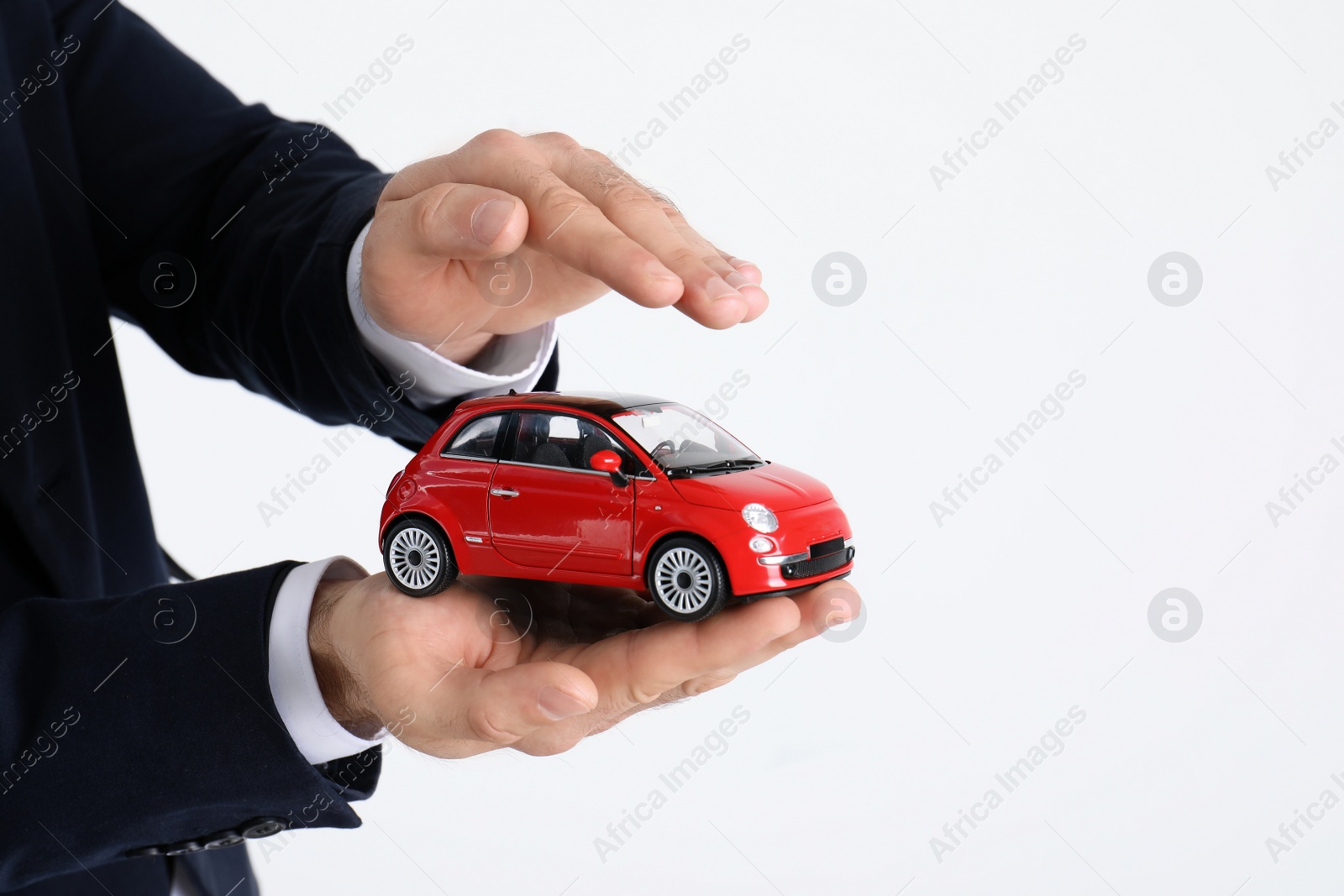 Photo of Male insurance agent holding toy car on white background, closeup. Space for text