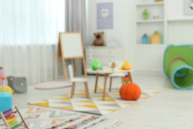 Photo of Blurred view of child`s playroom with different toys and furniture. Stylish kindergarten interior