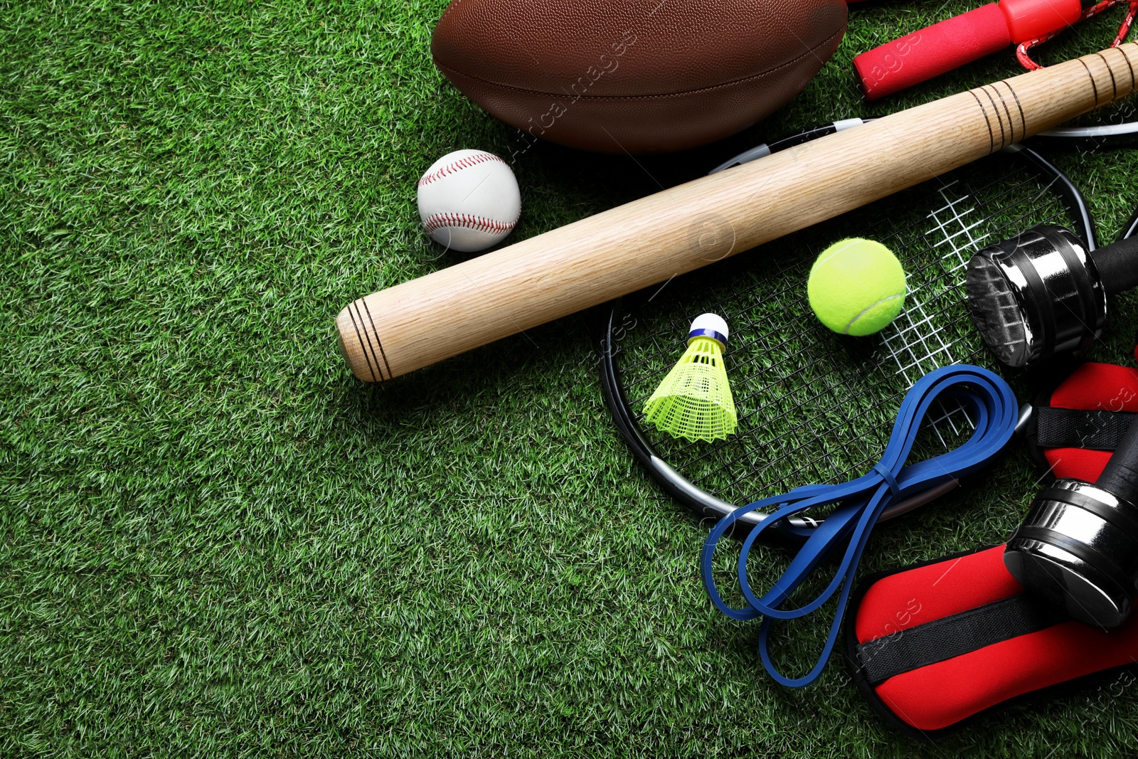 Photo of Set of different colorful sports equipment on green grass, above view. Space for text