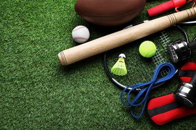 Set of different colorful sports equipment on green grass, above view. Space for text