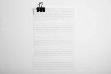 Photo of Sheet of paper with clip on white background, top view