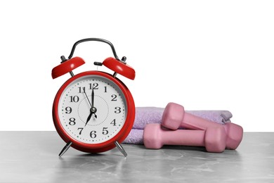 Photo of Alarm clock, towels and dumbbells on marble table against grey background. Morning exercise