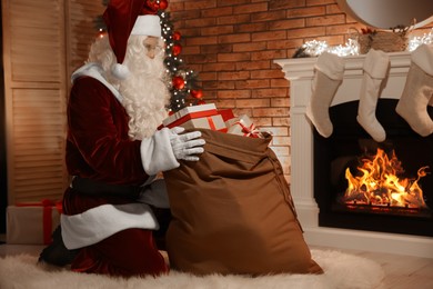 Photo of Santa Claus with sack of gifts in festively decorated room