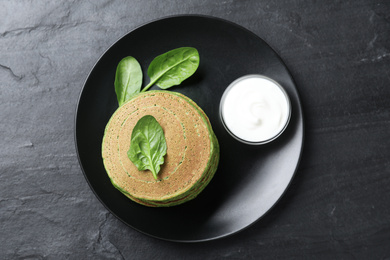 Photo of Tasty spinach pancakes served on black table, top view