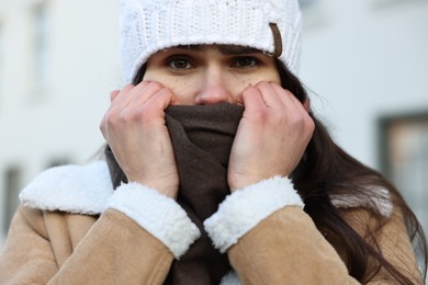 Sick woman in warm clothes on city street