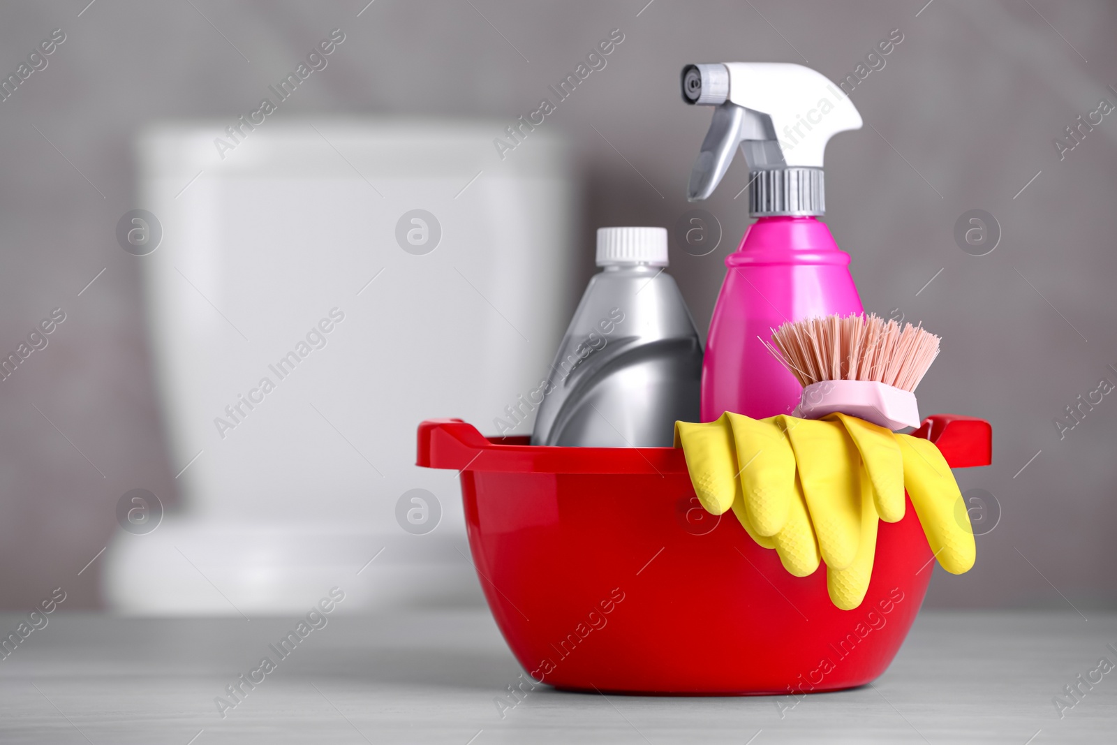 Photo of Plastic basin with cleaning supplies on table in bathroom, space for text