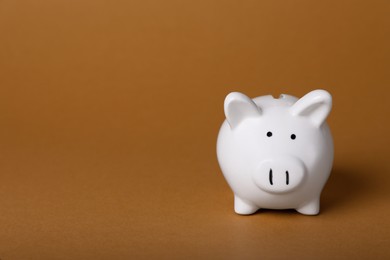 Photo of Ceramic piggy bank on brown background, space for text. Financial savings