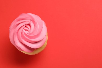 Photo of Delicious cupcake with bright cream on red background, top view. Space for text