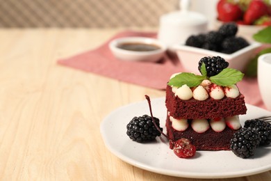 Photo of Piece of delicious red velvet cake with fresh berries served on wooden table, closeup. Space for text