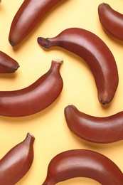 Photo of Tasty red baby bananas on yellow background, flat lay