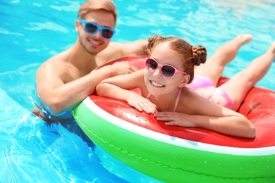 Photo of Young man with daughter in pool on sunny day