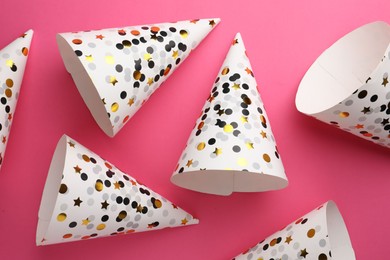 Beautiful party hats on pink background, top view