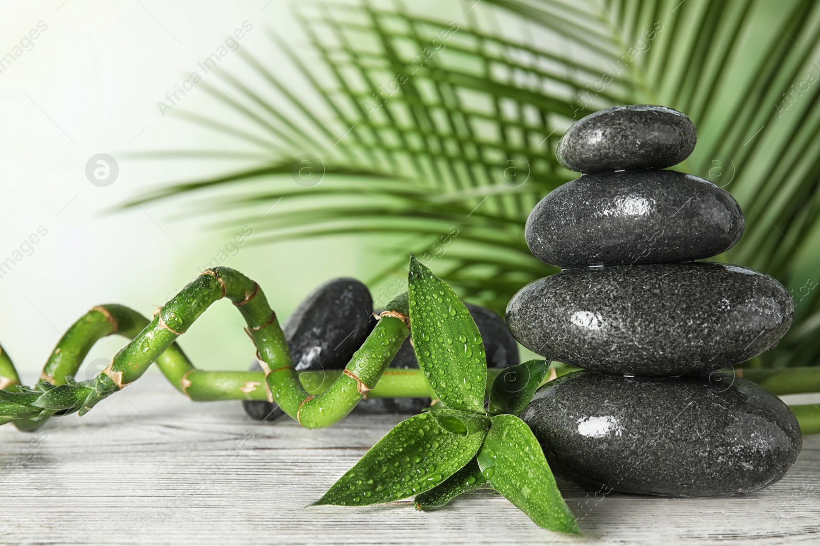 Photo of Spa stones and bamboo branches on wooden table. Space for text