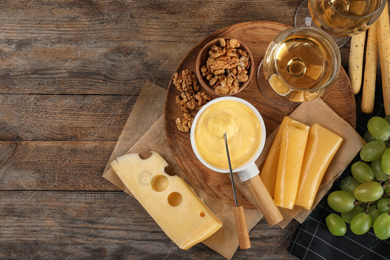 Photo of Flat lay composition with pot of tasty cheese fondue and products on wooden table, space for text