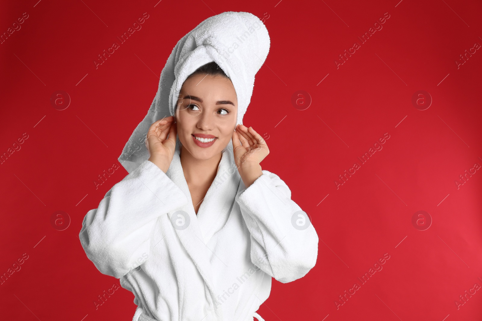 Photo of Beautiful young woman in bathrobe on red background. Space for text