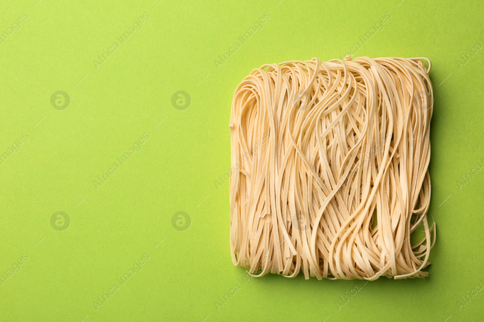 Photo of Block of quick cooking noodles on color background, top view. Space for text