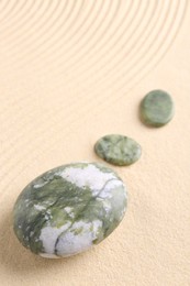 Photo of Zen garden stones on beige sand with pattern