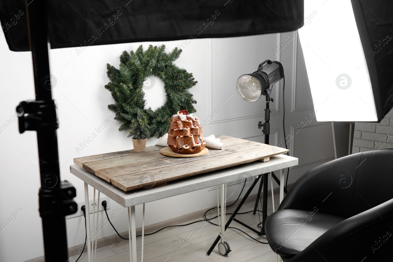 Photo of Professional equipment and Christmas composition with Pandoro cake on wooden table in studio. Food photography