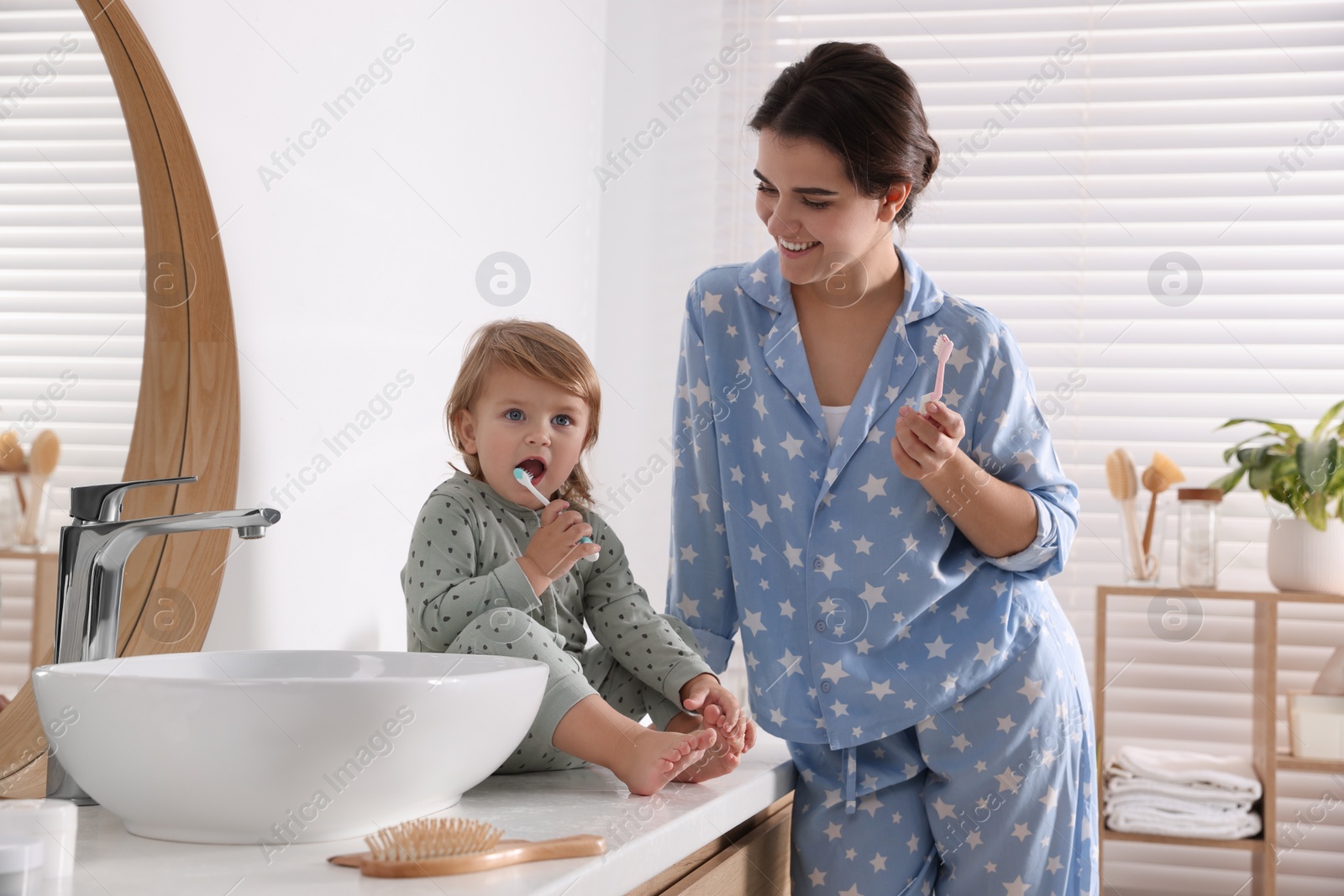 Photo of Mother and her daughter brushing teeth together in bathroom