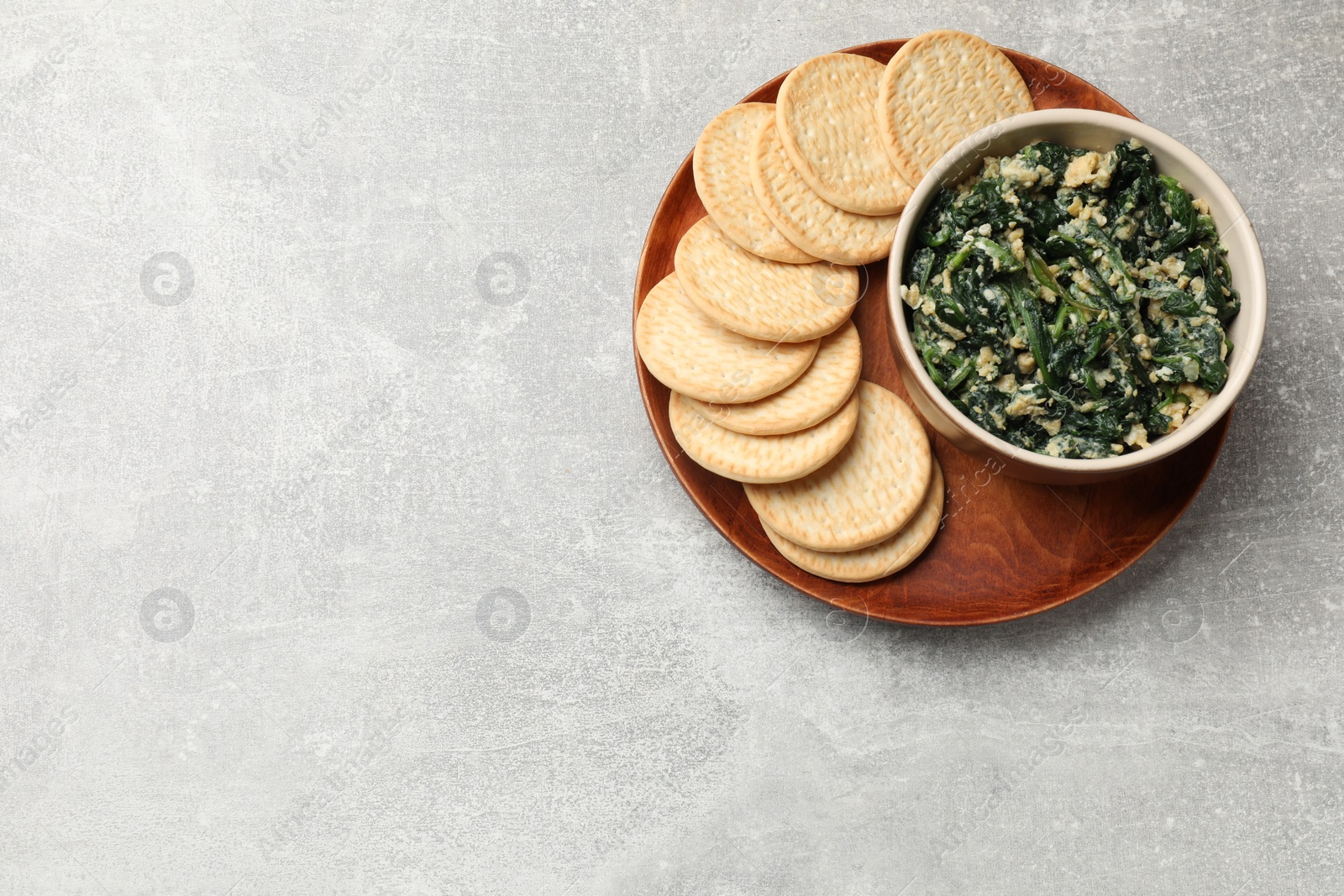 Photo of Tasty spinach dip with egg and crackers on grey table, top view. Space for text