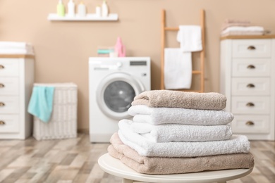 Stack of towels on table against blurred background, space for text