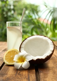 Photo of Composition with glass of coconut water and lemon on wooden table