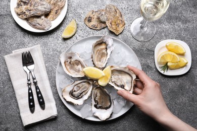 Photo of Woman eating tasty fresh oysters at grey table, top view