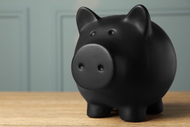 Photo of Ceramic piggy bank on wooden table, closeup. Space for text