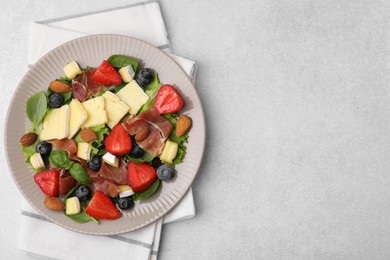 Photo of Tasty salad with brie cheese, prosciutto, almonds and berries on light grey table, top view. Space for text