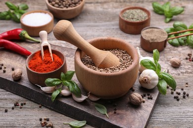 Photo of Mortar with pestle and different spices on wooden table