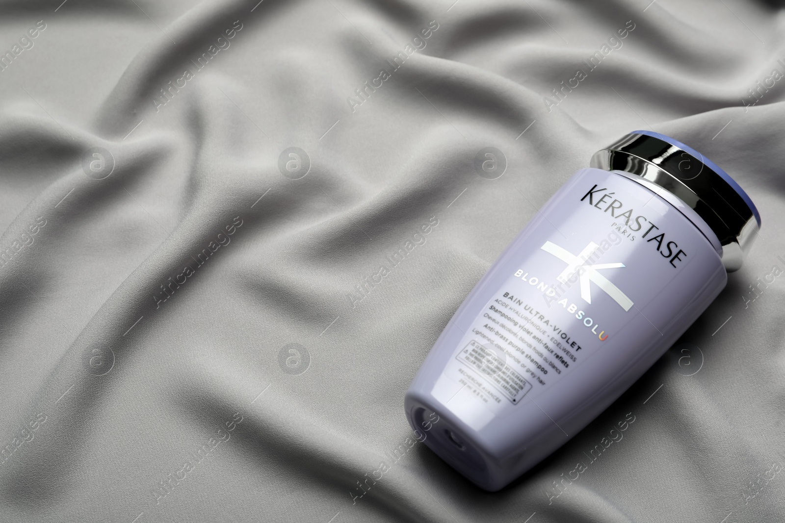Photo of MYKOLAIV, UKRAINE - SEPTEMBER 07, 2021: Kerastase shampoo on grey fabric. Space for text