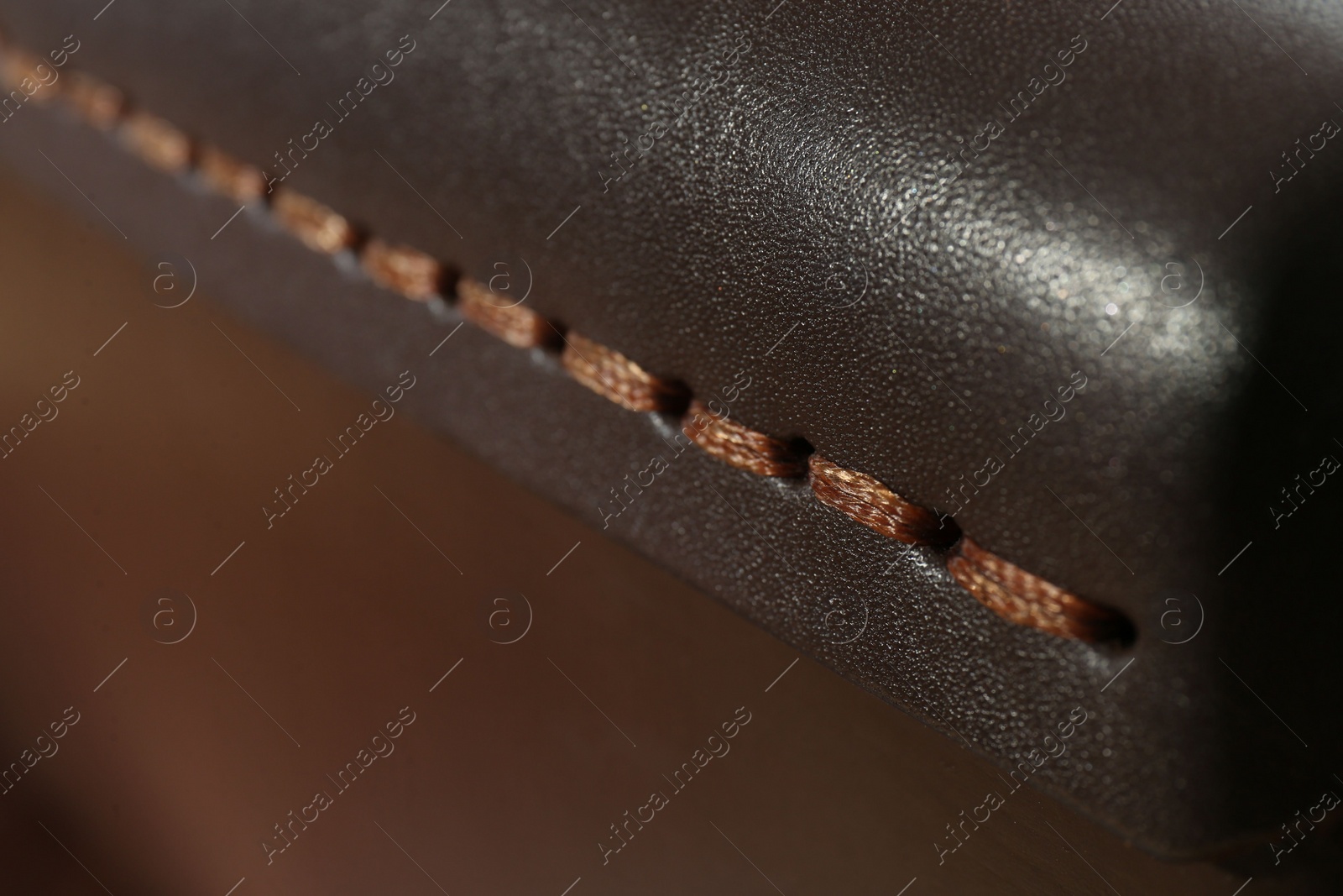 Photo of Dark leather with brown seam as background, closeup