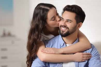 Cute couple. Woman kissing her smiling boyfriend at home