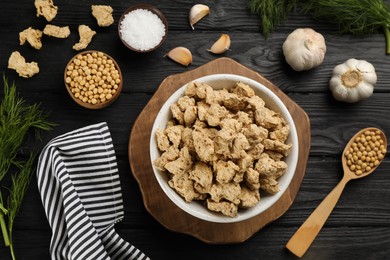 Dried soy meat in bowl on black wooden table, flat lay