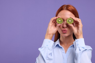 Funny woman covering eyes with halves of fresh kiwi on violet background, space for text