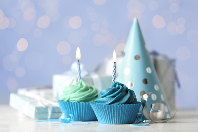 Photo of Delicious birthday cupcakes with cream and burning candles on white table
